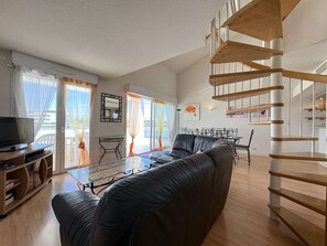 Ein modernes Wohnzimmer mit einer Couch, einem Fernseher und einer Wendeltreppe.