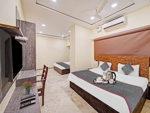 A hotel room with a bed, a desk with a TV, a chair, a ceiling fan, and an air conditioning unit. - Collection O Yash Inn (Chennai)
