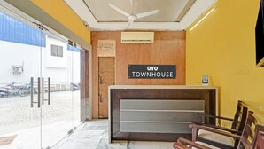 Et receptionsområde med et skilt der viser 'OYO TOWNHOUSE', en loftsvifte og udsigt udad.