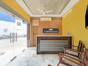 A reception area with a sign reading 'OYO TOWNHOUSE,' a ceiling fan, and a view of the outside. - Collection O Yash Inn (Chennai)