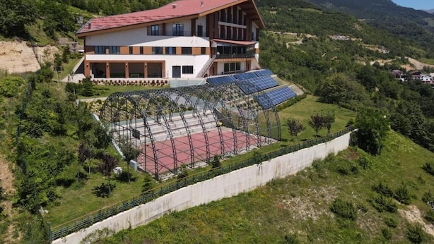 Ein zweistöckiges Gebäude mit rotem Dach, Solaranlagen und einer Achterbahn.