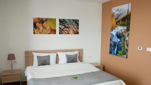 Ein Hotelzimmer mit einem Bett, einem Nachttisch, einer Lampe und drei Wandbildern.