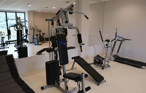 A gym with various exercise equipment including a bench, weight machines, and treadmills.