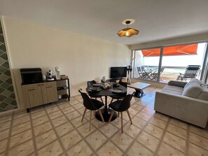 Ein Essbereich mit Tisch, Stühlen, einem Fernseher und einer Couch.
