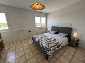 Ein Schlafzimmer mit einem Bett, zwei Nachttischen, einer Pendelleuchte und einem Fenster.