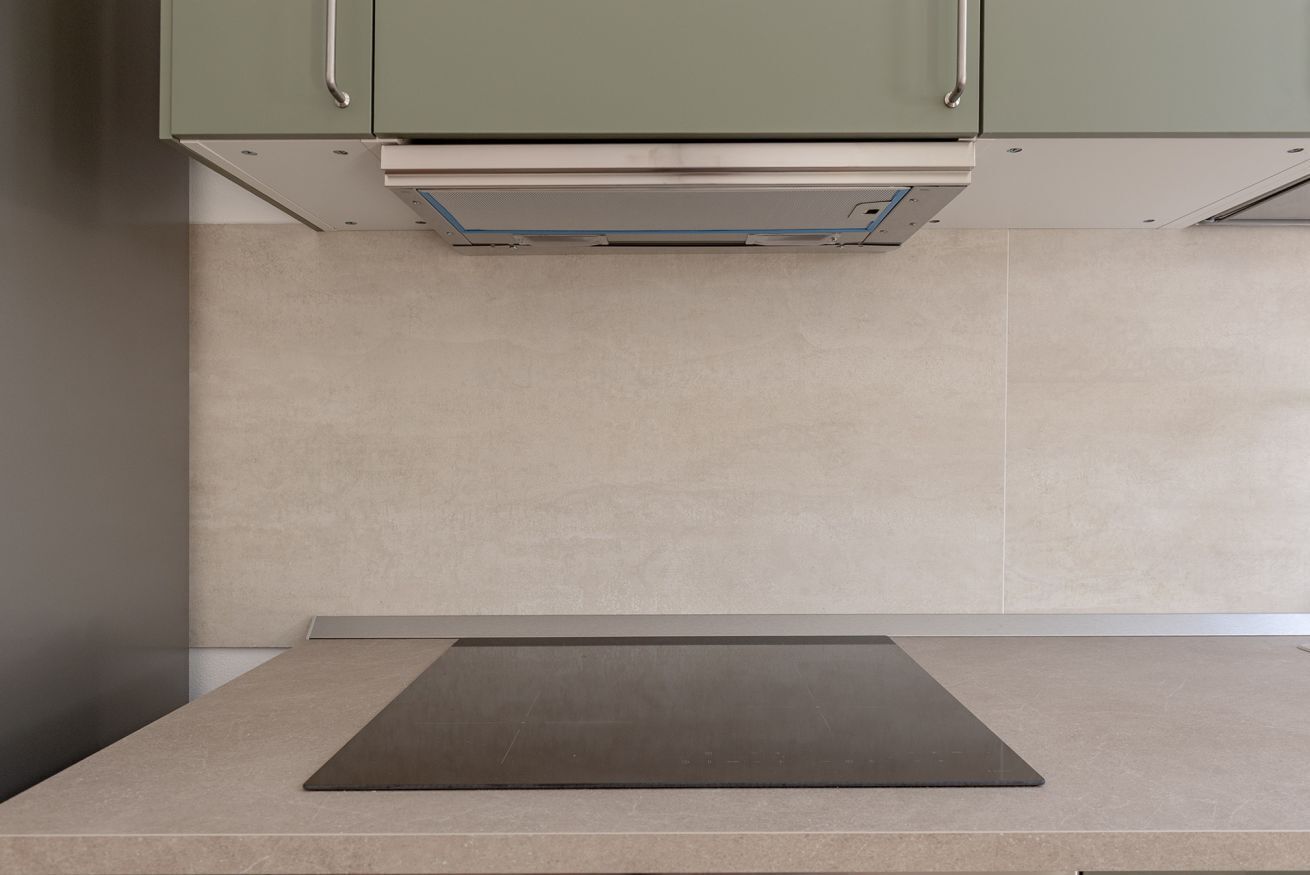 A kitchen with a countertop, cabinets, and a range hood.