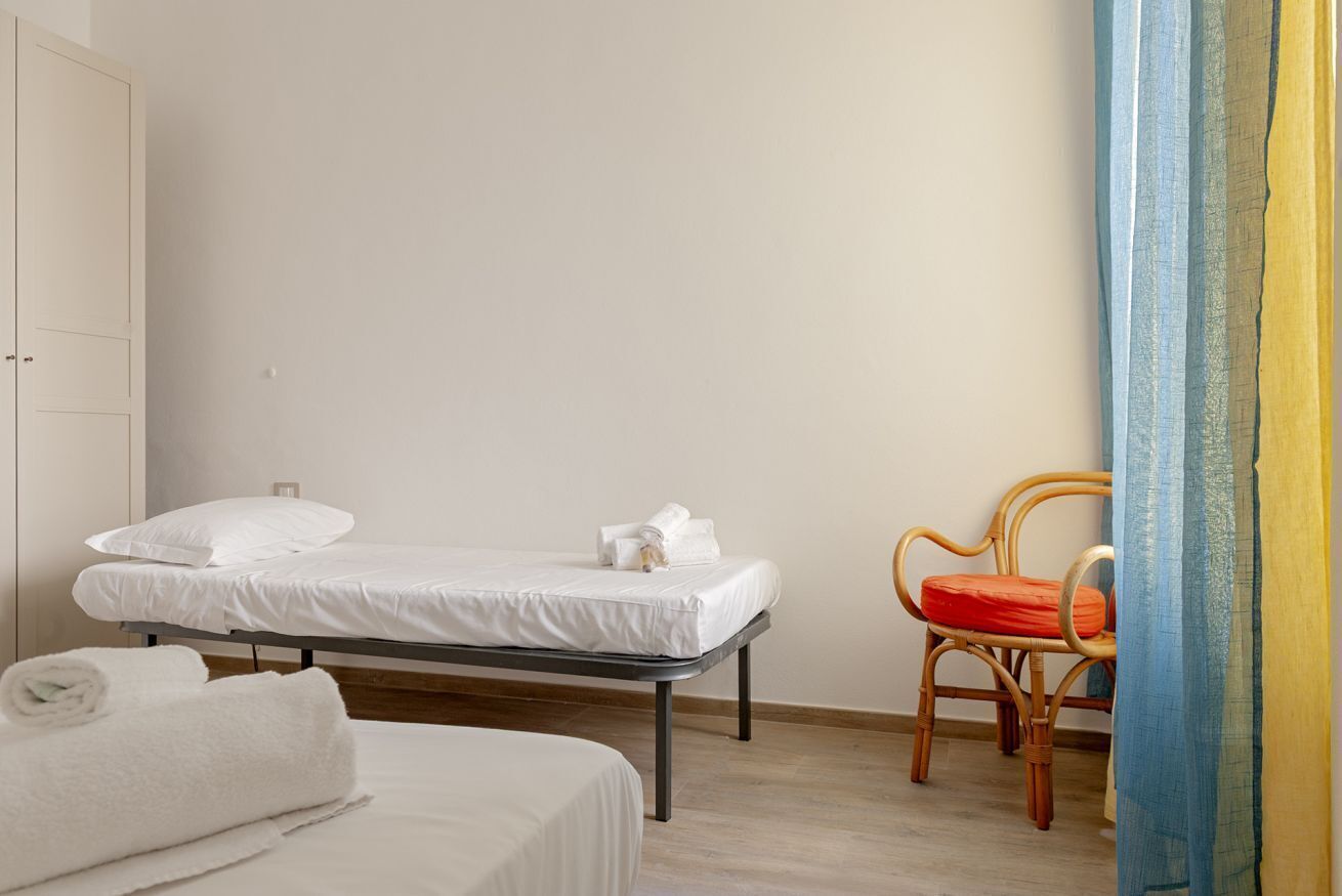 Un dormitorio con cama, una silla y un armario.