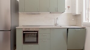 Cuina amb forn integrat, rentaplats i nevera d'acer inoxidable.
