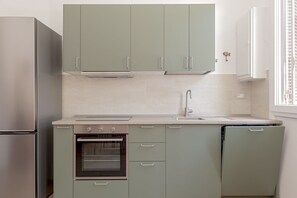 A kitchen with a built-in oven, a dishwasher, and a stainless steel refrigerator. - Domio | Italian Summer by the Sea (Lido di Camaiore)