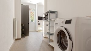 Zona de bugaderia amb una rentadora, una assecadora i un microones damunt d'una estantàlia.