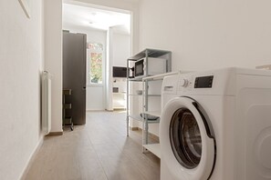 A laundry area with a washing machine, a dryer, and a microwave on a shelf. - Domio | Italian Summer by the Sea (Lido di Camaiore)