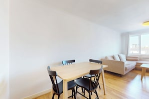 Ein modernes Wohnzimmer mit einem Holzesstisch, vier Stühlen, einer Couch und einem kleinen Couchtisch.