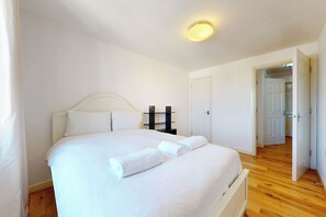 A bedroom with a bed, bedside tables, a door, and a hallway leading to another room. - Amazing 1BR Flat w/ Easy Access to City Centre (London)