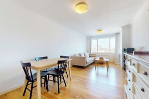 Eine moderne Wohnung mit Essbereich, Sofa und Blick auf die Stadt.