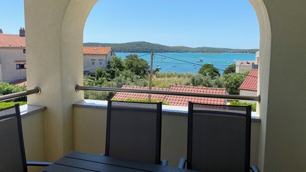 Uma varanda com vista para a costa, incluindo um corpo de água e colinas ao longe.