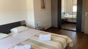 Quarto de hotel com cama, mesa de cabeceira, luminária, armário e espelho.