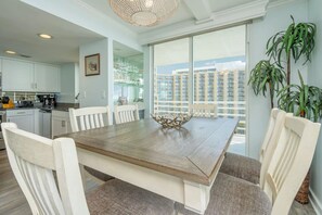 A dining area with a wooden table, white chairs, and a decorative bowl. - N Hampton 901 in Kingston, Oceanfront, Pool, Beach (Myrtle Beach)