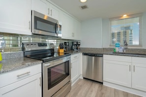 A modern kitchen with stainless steel appliances, granite countertops, and white cabinetry. - North Hampton 901 Oceanfront in/out pool/Beach (Myrtle Beach)