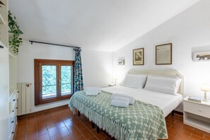 A bedroom with a bed, a window with curtains, a radiator, and a wall-mounted shelf. - GuestHost - La Pineta Charming Home in Tirrenia (Tirrenia)