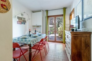 A dining area with a table set for four, a television, and a view of the outdoors. - GuestHost - La Pineta Charming Home in Tirrenia (Tirrenia)