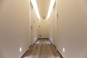 A long, narrow hallway with white walls and wooden flooring, leading to a door at the end. - Mas Collection - Bari Monfalcone (Bari)
