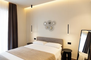 A modern hotel room with a large bed, a wall-mounted artwork, and a mirror.