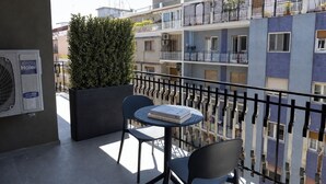 Un balcón con una mesa, sillas, una planta en maceta y un equipo de aire acondicionado Haier.