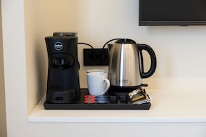 A coffee maker, a mug, and a kettle on a countertop.