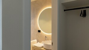 Un baño con un espejo redondo, un lavabo y un perchero para toallas.