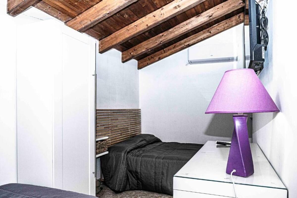 Un dormitorio con cama, mesita de noche, lámpara y techo de madera.