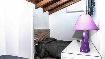 A bedroom with a bed, a nightstand, a lamp, and a wooden ceiling.