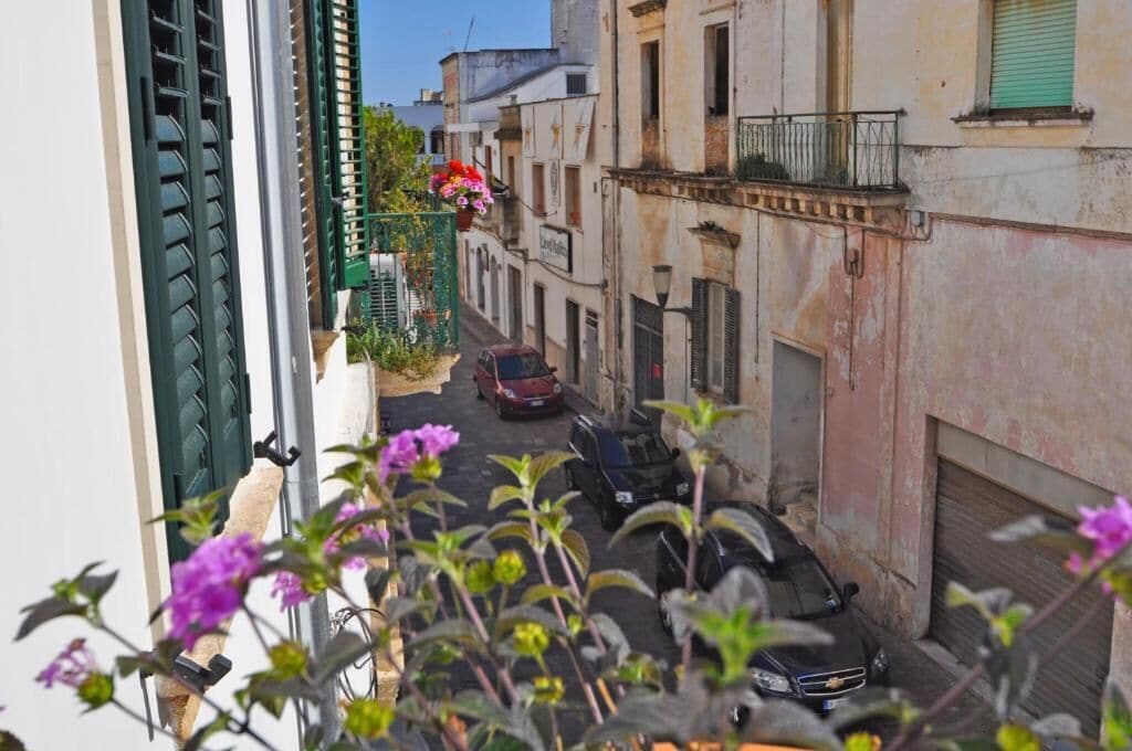 Una stretta via fiancheggiata da auto parcheggiate e edifici.
