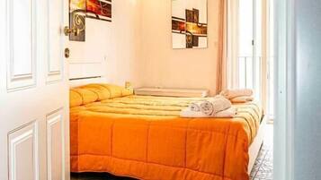 Quarto com uma cama grande, uma porta e um chão estampado.