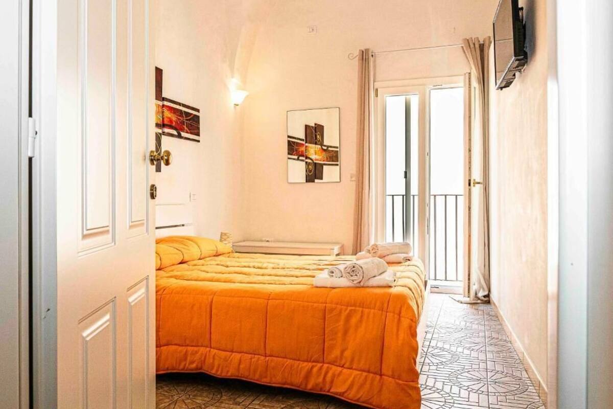 Una habitación de hotel con una cama grande, un televisor montado en la pared y una puerta que da a un balcón.