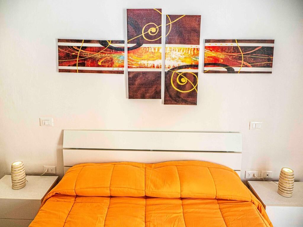 Een hotelkamer met een bed, een wit hoofdeinde en een abstract kunstwerk aan de muur.