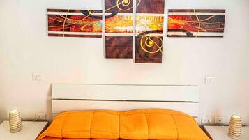 A hotel room with a bed, a white headboard, and a wall-mounted abstract art piece.