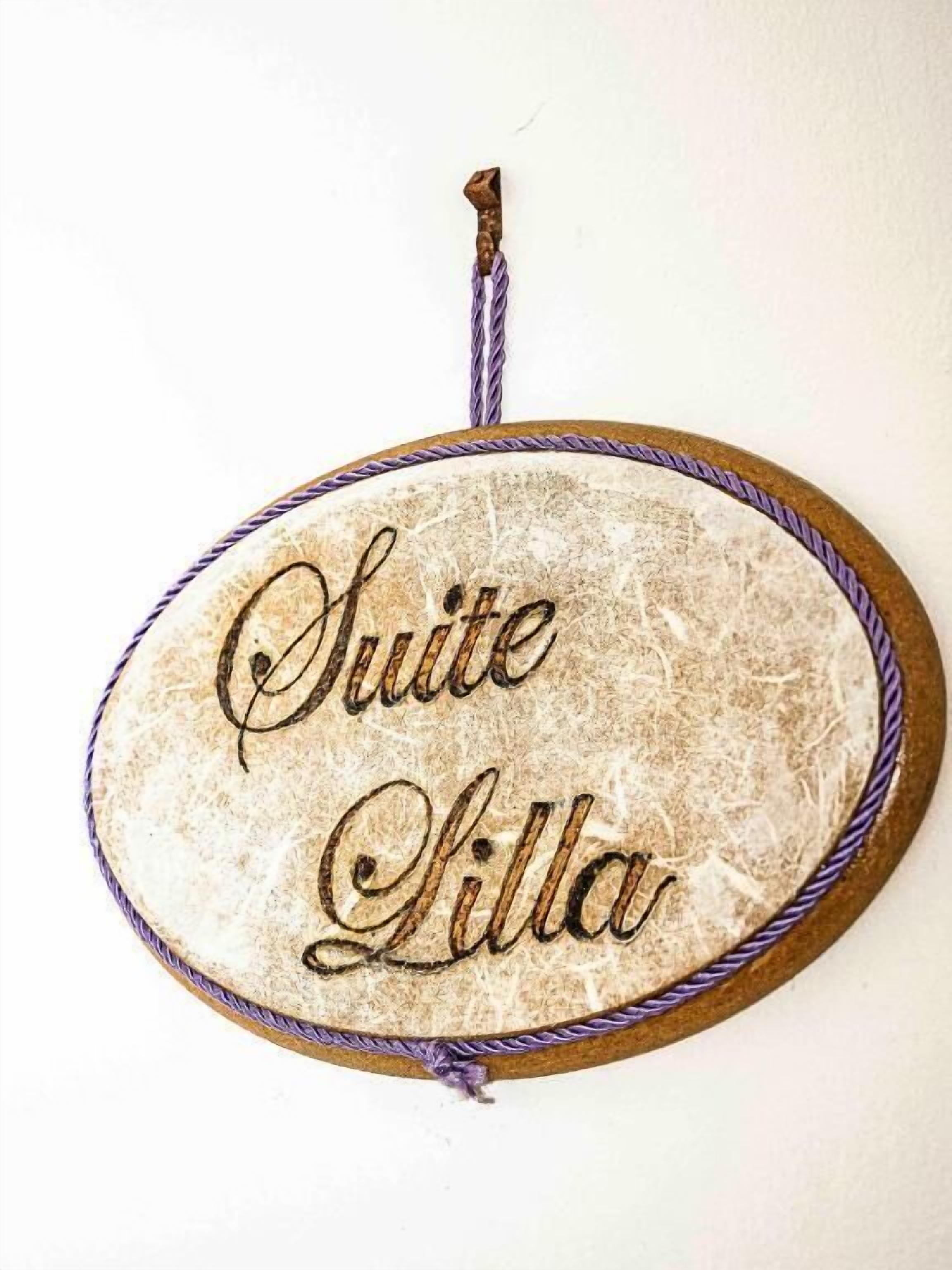 Un cartel con el texto 'Suite Lilla' sobre un fondo texturizado.