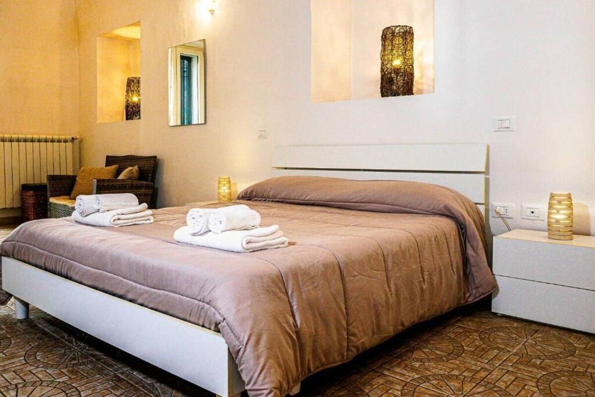 Una habitación de hotel con cama, mesitas de noche, espejo y radiador.