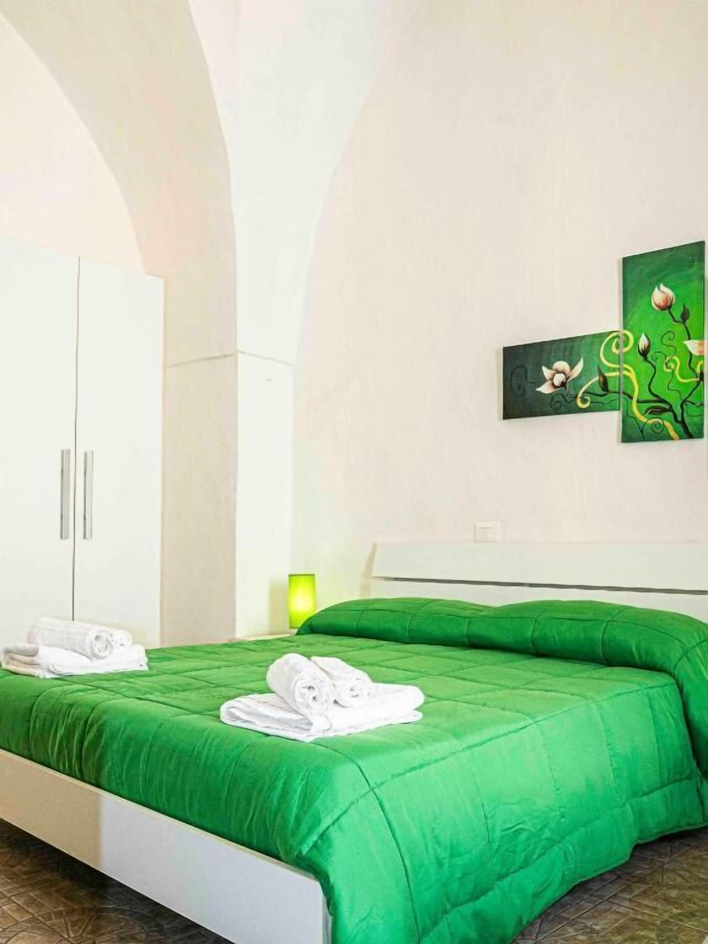 A hotel room with a bed, a wardrobe, and a wall-mounted artwork.