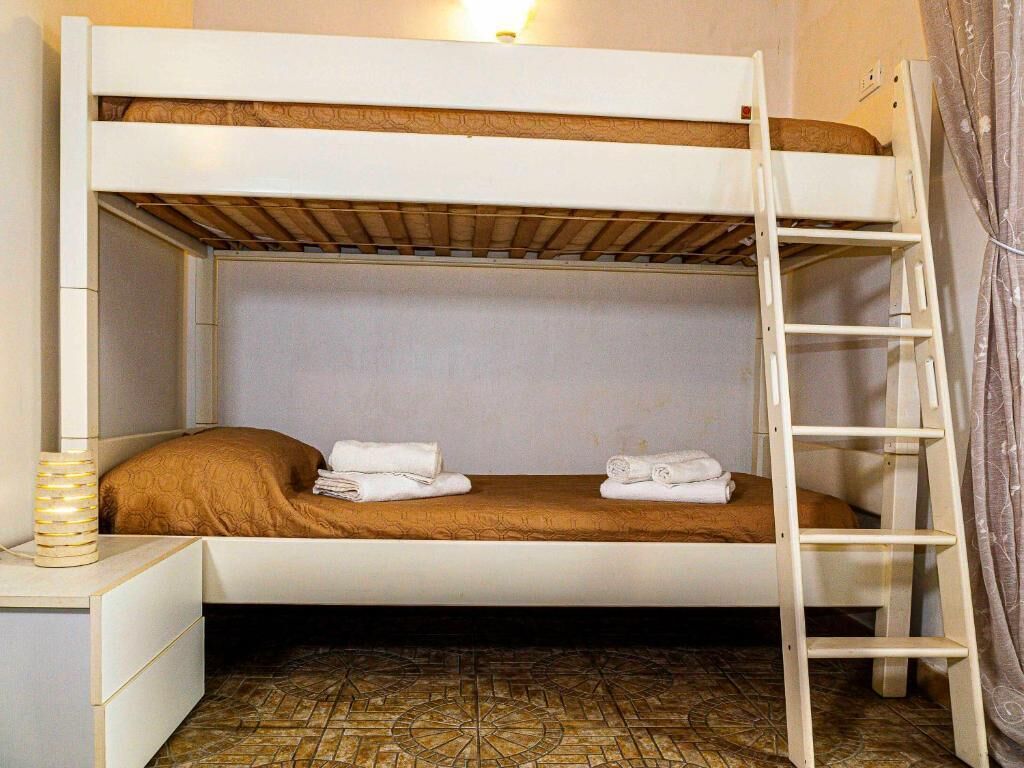Ein Stockbett mit einer Leiter, ein Nachttisch mit einer Lampe und ein gemusterter Boden.