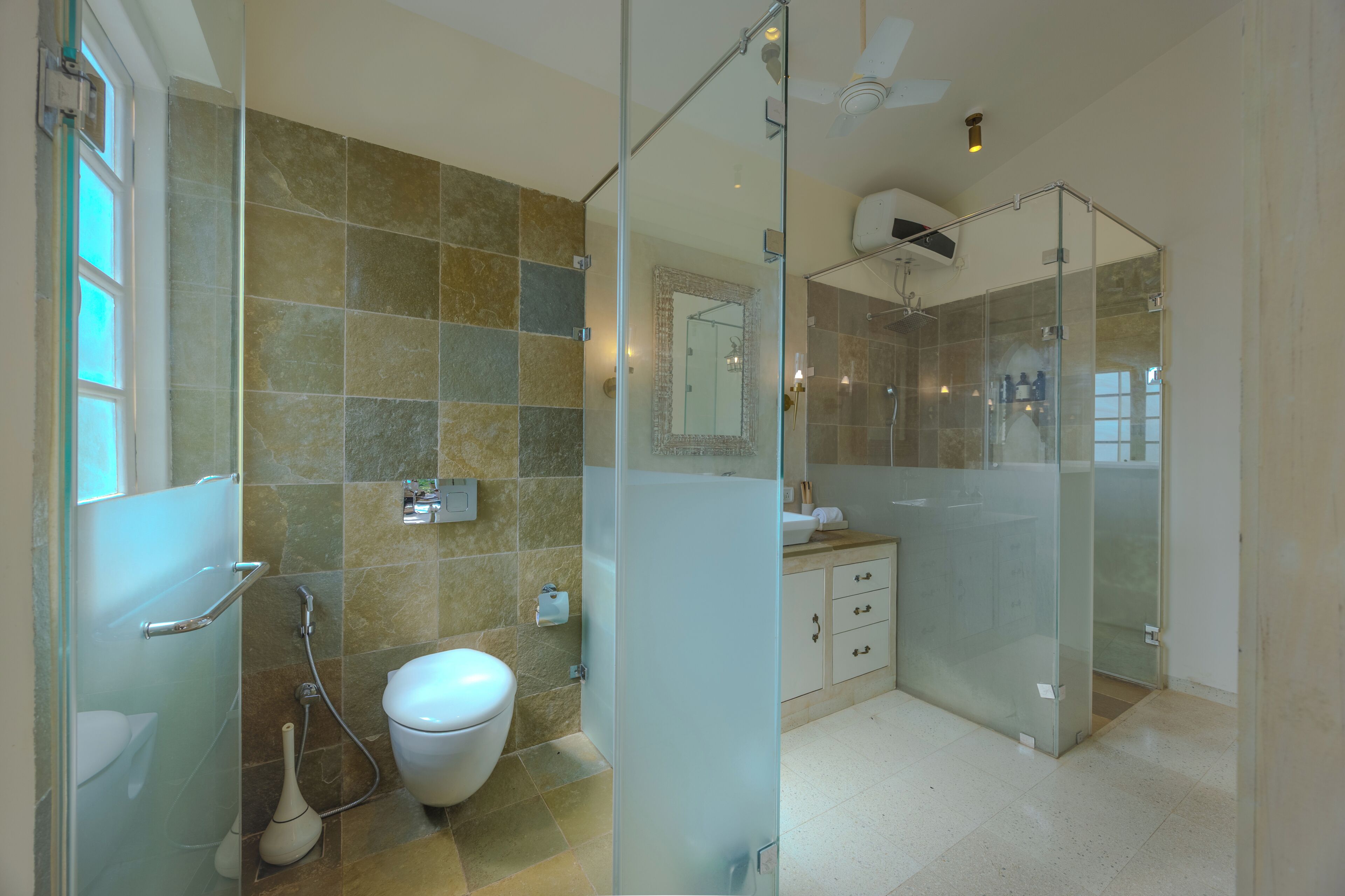 A modern bathroom with a glass shower enclosure, a toilet, and a vanity with drawers.