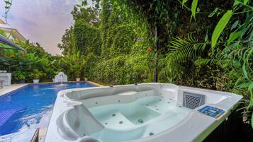 Un bain à remous dans un jardin luxuriant, avec une piscine.