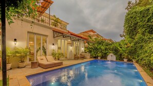 A swimming pool with lounge chairs, a covered patio, and potted plants. - ELIVAAS Elysium 3BHK Villa With Jacuzzi (Anjuna)