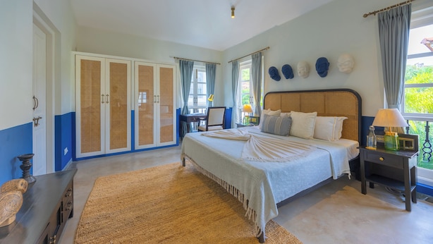 A bedroom with a bed, a desk, a wardrobe, and a window with curtains. - ELIVAAS Elysium 3BHK Villa With Jacuzzi (Anjuna)