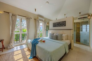 Un dormitorio con cama, ventana con cortinas, equipo de aire acondicionado, una obra de arte colgada en la pared y cabina de ducha de vidrio.