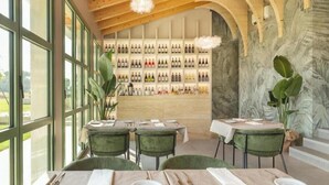 Een restaurant met een wijnmuur, houten plafond en grote ramen.