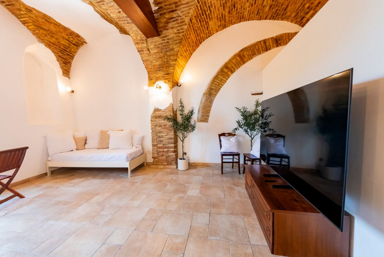 Une pièce confortable avec un lit, un coin salon, une télévision et un mur en pierre.