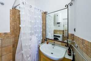 Un bagno con tenda da doccia, lavandino, specchio e portasciugamani.