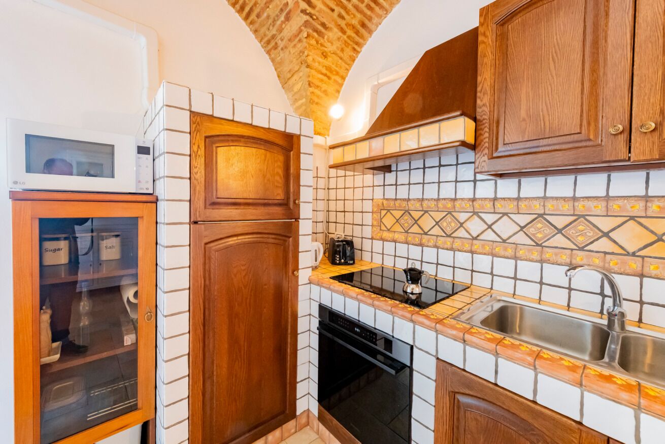 A kitchen with a microwave, cabinets, a sink, and a tiled backsplash.