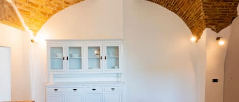 Una habitación con un armario blanco, suelo de baldosas y ladrillo visto en el techo.